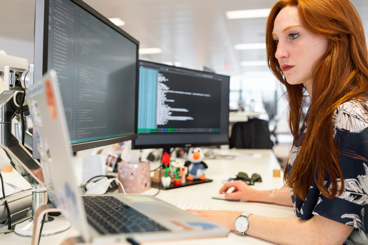A person working at a desk with several monitors